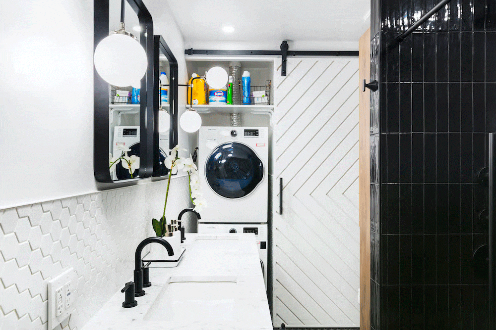 White bathroom with two sink top and a view of the barn door with washer dryer after renovation