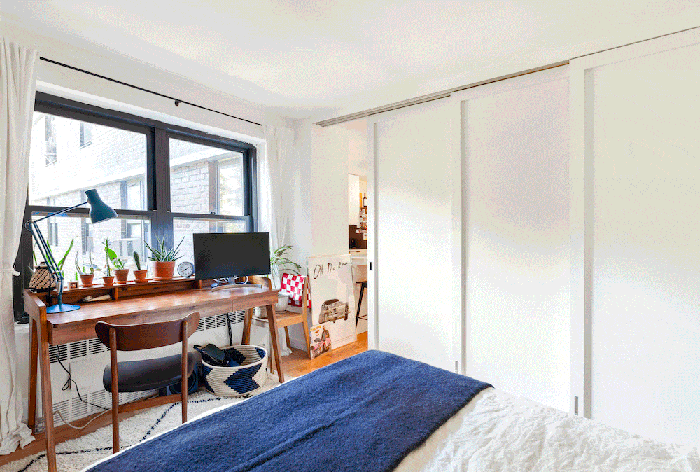 large black framed window in a white bedroom with barn door after renovation
