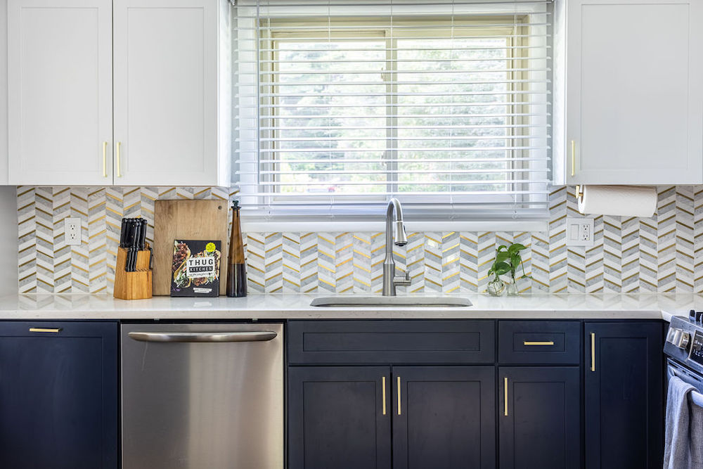 Blue and white kitchen cabinets with undermount sink and a window after renovation