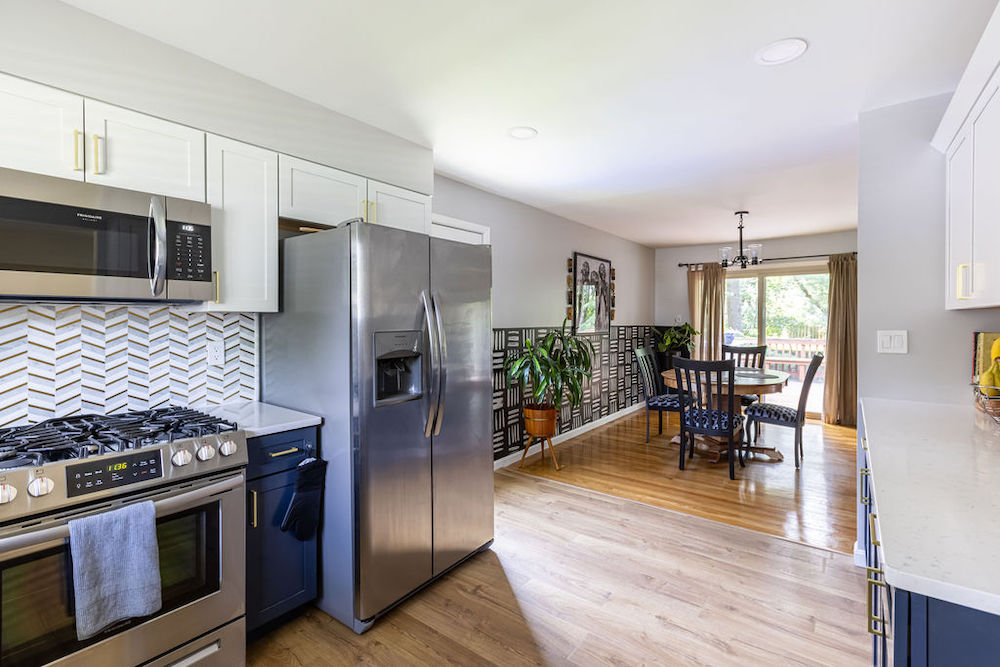 Blue and white kitchen with fishbone backsplash overlooking the dining area after renovation