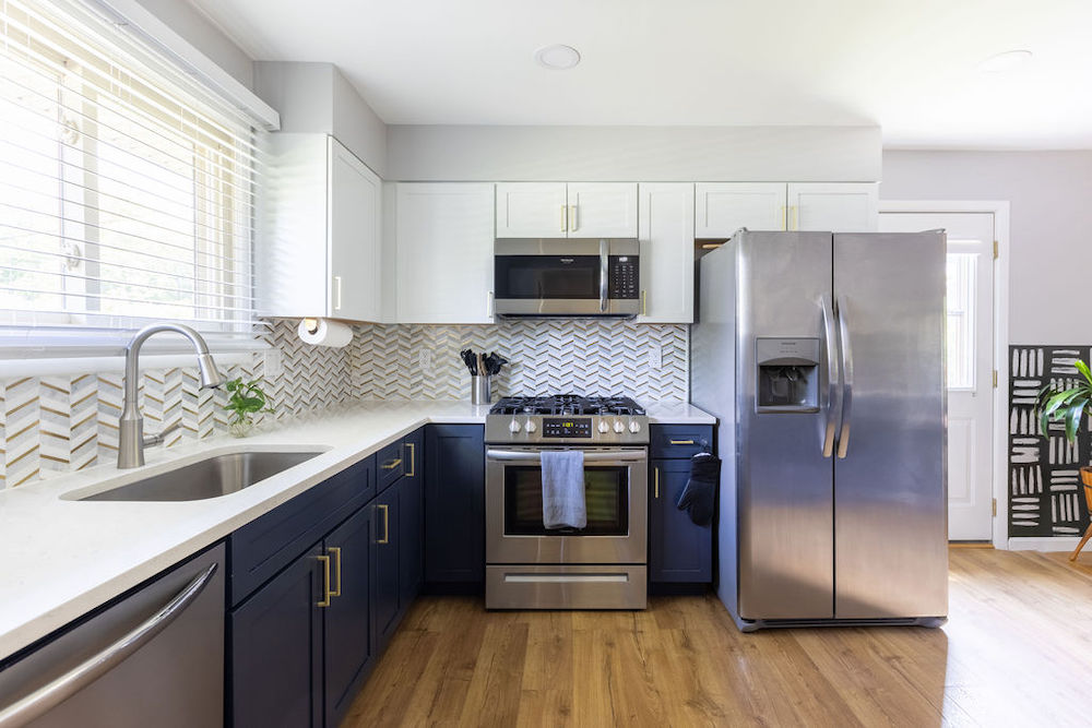 Blue and white kitchen with appliances and large window after renovation