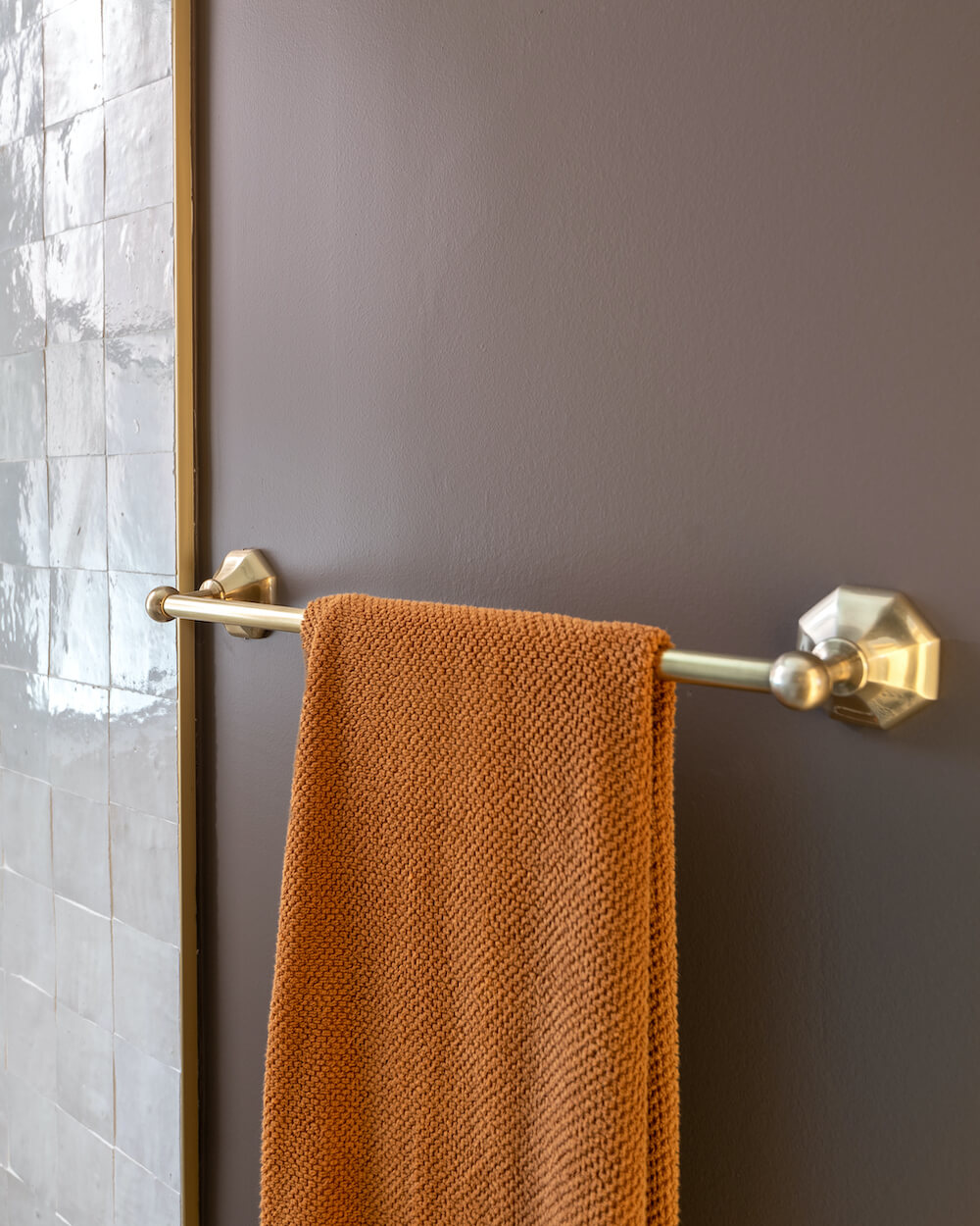 bathroom with plum walls, brass hardware, and white square tile
