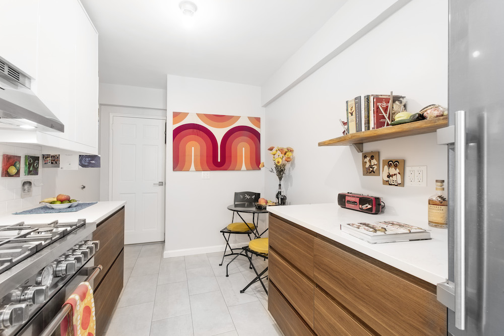 kitchen with white walls and natural wood cabinets and floating shelf and stainless steel appliances and floor tiling after renovation