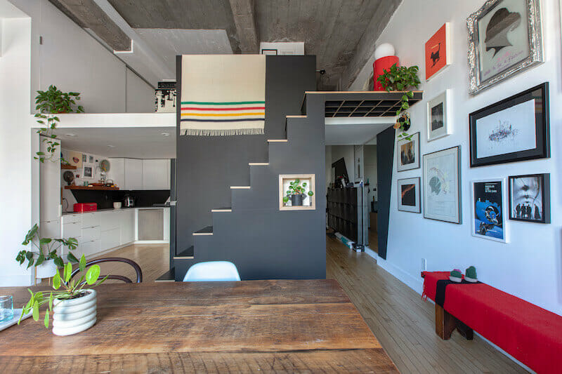 View of the black staircase leading to loft along with dining area and kitchen after renovation
