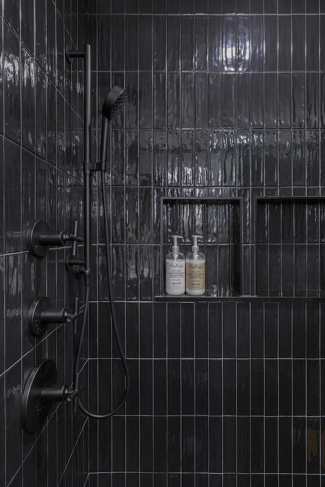 All black shower area with built in wall shelf and black bathroom fitting after renovation