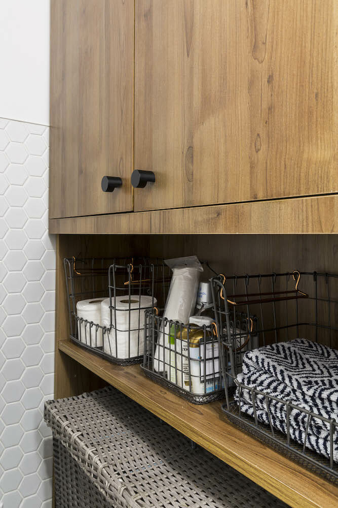 Walnut shelving cabinet with black knobs and toiletry after renovation