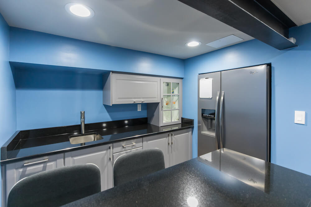 Kitchen area with sink under grantite countertop and gray cabinetry after renovation