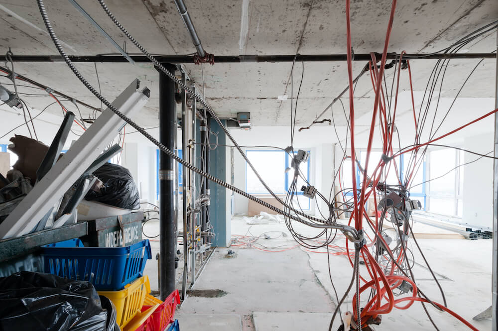 A gut renovation with tangled electrical wires hanging from the ceiling