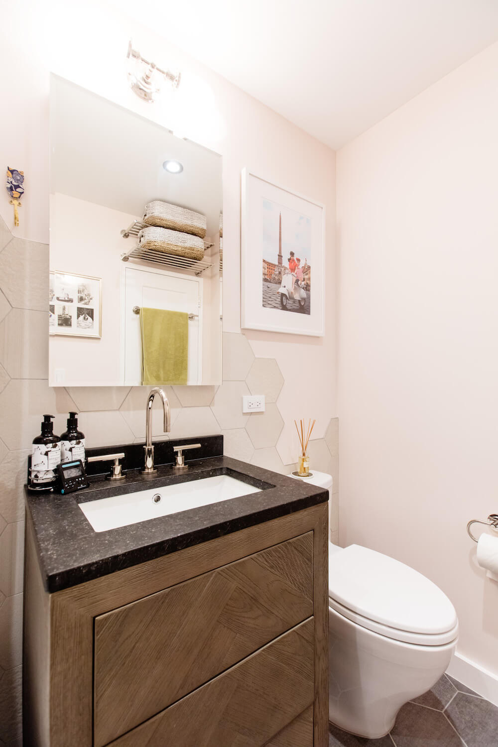 Large vanity mirror over white sink and black countertop with herringbone vanity after renovation