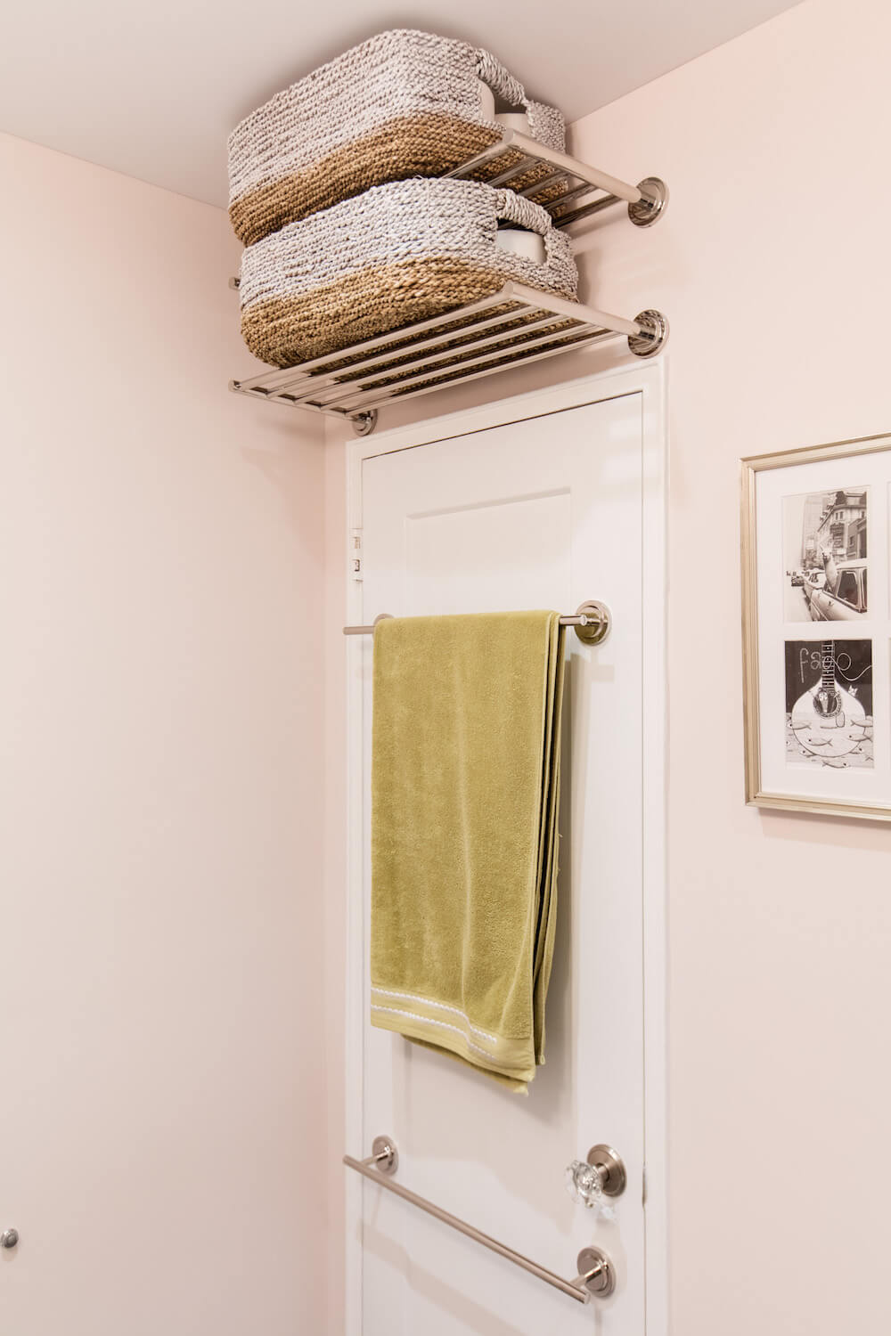 Shelves over white door with woven baskets and stainless steel towel bar after renovation