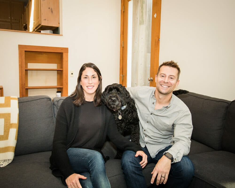 Happy homeowners sitting on the couch with their dog