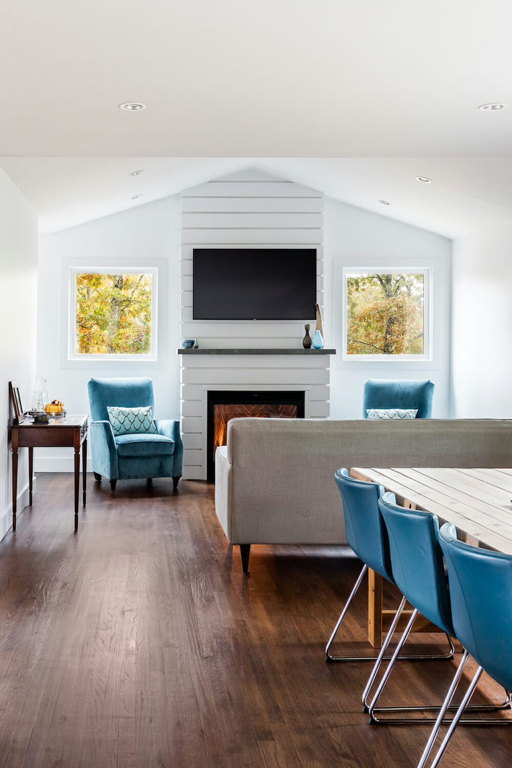 open living and dining room combo with hardwood floors and white brick fire place after renovation