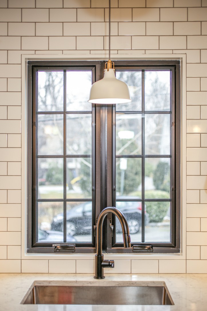 white subway tiles with black grout in kitchen with black framed window and sink with black faucet after renovation