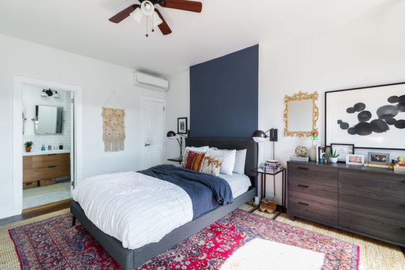 white bedroom with gray bed and blue wall behind and a dark chest of drawers after renovation