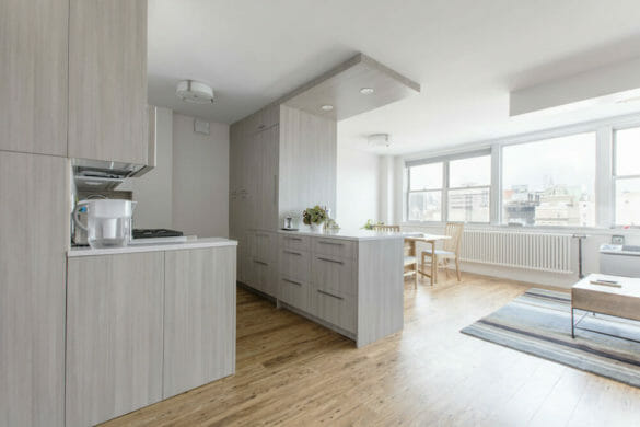 open kitchen with gray cabinets and peninsula island and hardwood floors and large window and flush mounted ceiling lights and white walls after renovation