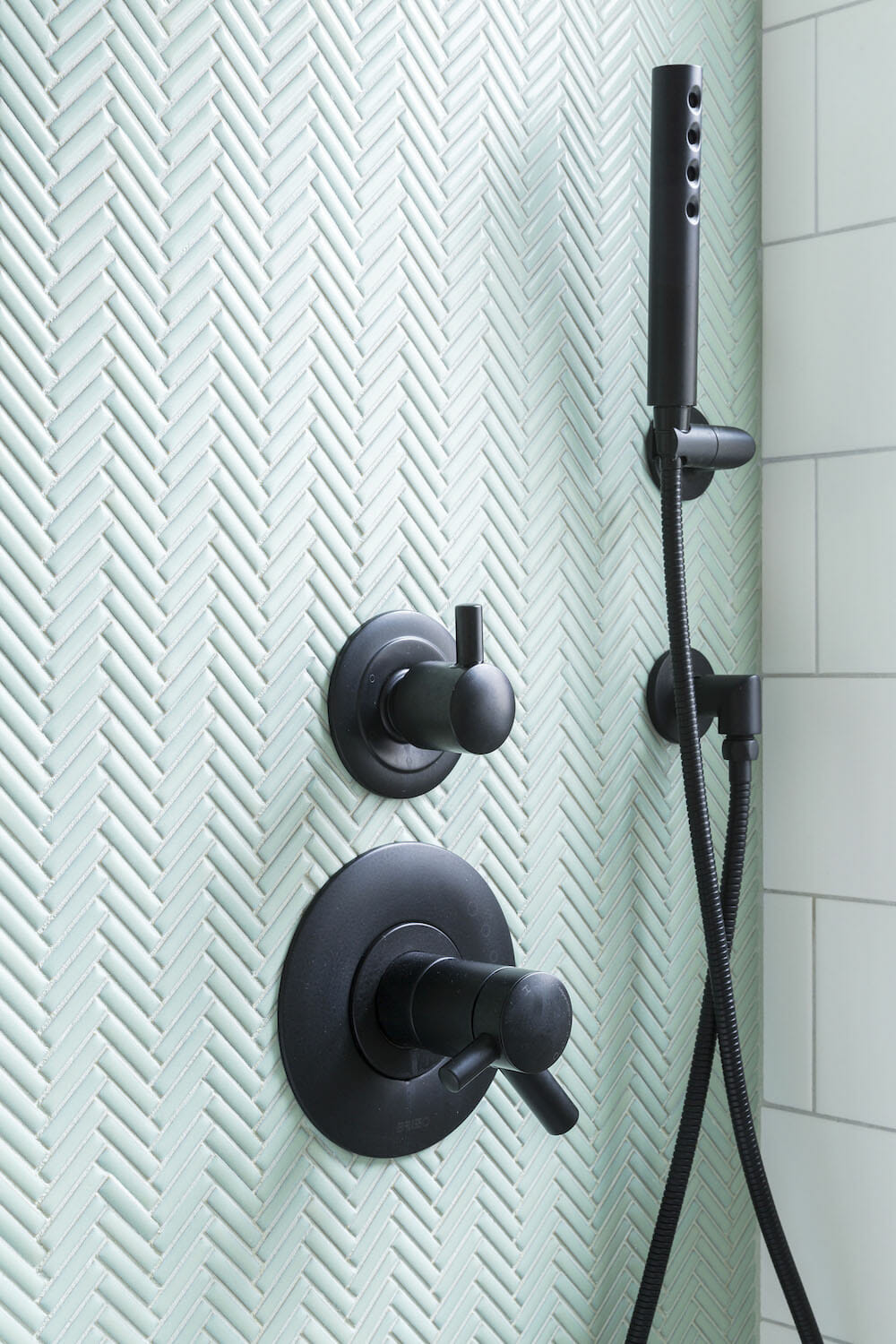 3d design pattern on shower wall with black fixtures and white tiles on other wall after renovation