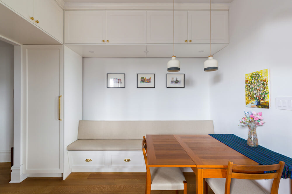 breakfast area with overhead storage cabinets and built-in seat with storage and pendant lights and hardwood floors after renovation