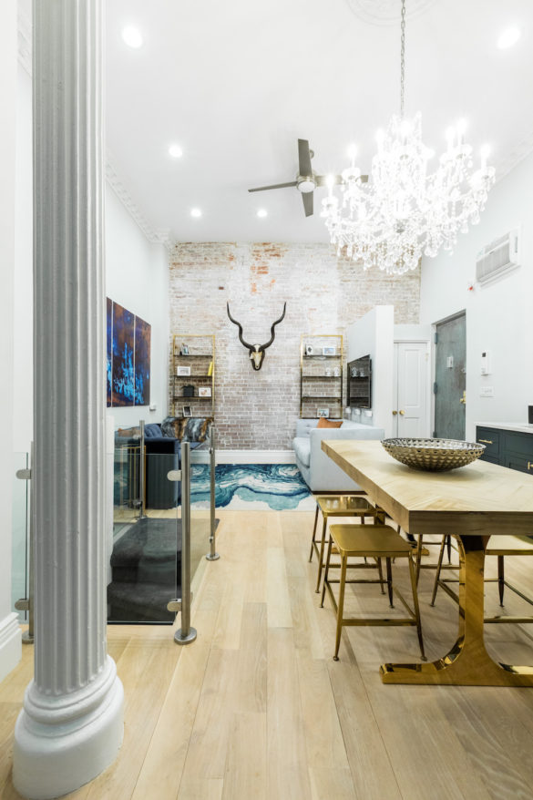 white pillar near dining table with chandelier in ceiling and brick wall after renovation