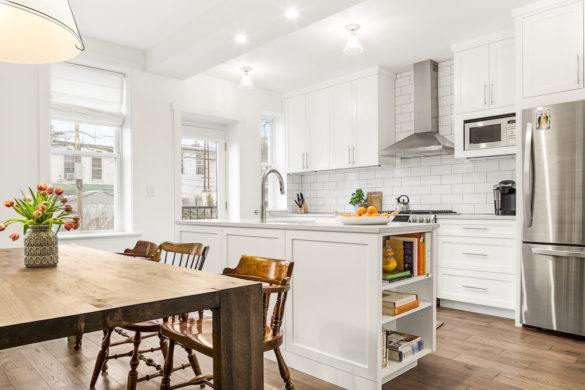 white kitchen island with marble countertop in an open kitchen with white kitchen cabinets after renovation