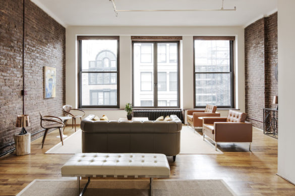 large windows for a brick walled living room and glossy brown floor after renovation