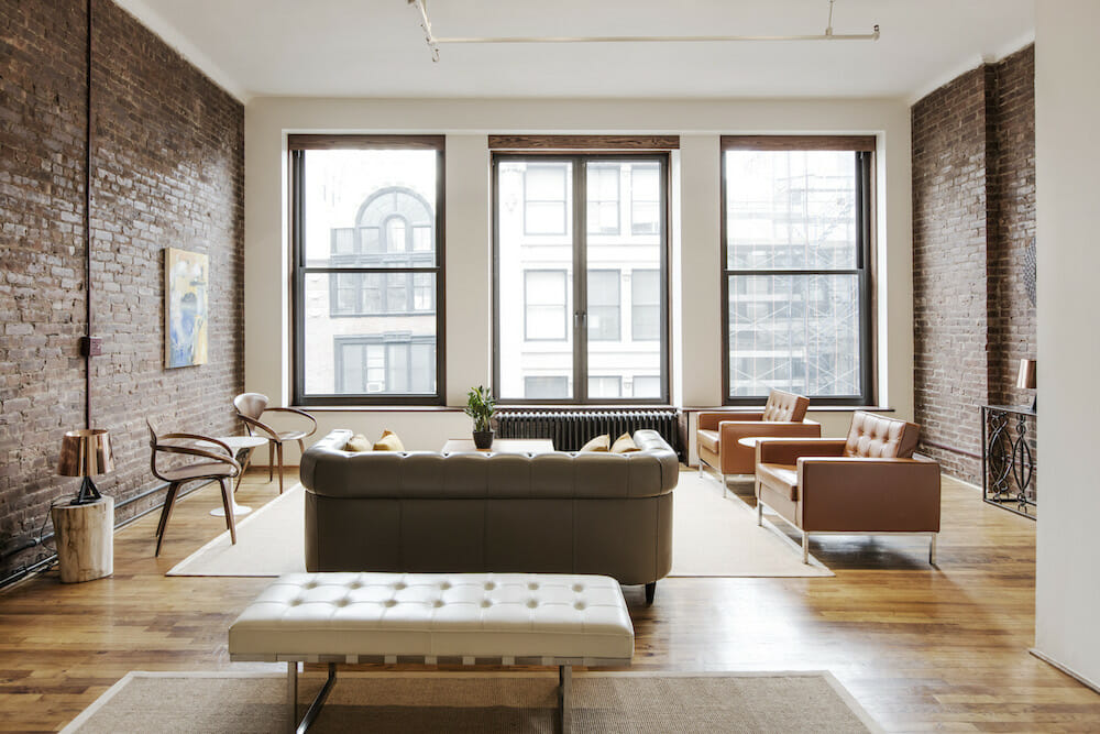 large windows for a brick walled living room and glossy brown floor after renovation