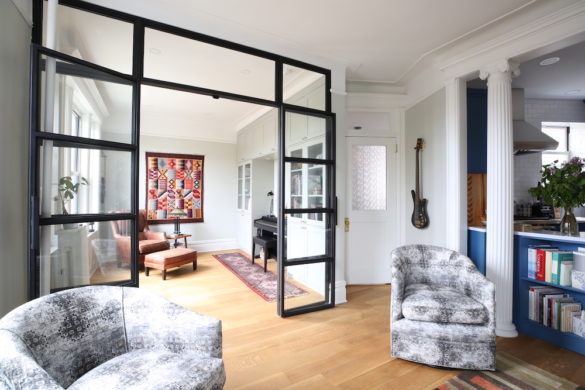 glass partition with black frames between rooms and hardwood floors and white walls after renovation